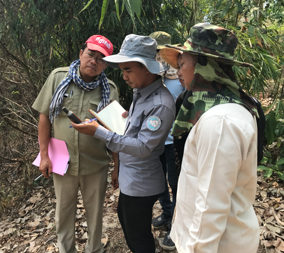 officials looking at a GPS in a tropical forest
